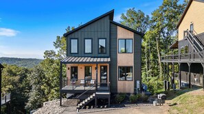 A two-story modern house with a balcony, a staircase, and a view of the surrounding forest. - 5BR Luxury Cabin・Pool・Near Dollywood / Water Parks (Sevierville)