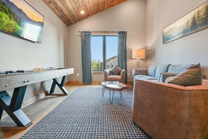 A cozy living room with a pool table, a sofa, a chair, and a window with curtains. - 5BR Luxury Cabin・Pool・Near Dollywood / Water Parks (Sevierville)
