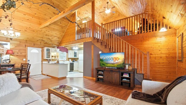A spacious living area with a wooden staircase, a television, and a cozy seating arrangement. - Wildcat Retreat, Cozy Norris Lake Cabin Getaway (New Tazewell)