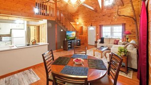 A wooden cabin interior with a dining area, kitchen, living room, and a staircase. - Wildcat Retreat, Cozy Norris Lake Cabin Getaway (New Tazewell)