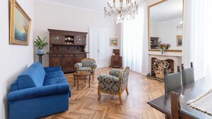 Ein Wohnzimmer mit einem blauen Sofa, Holzmöbeln, einer Kandelaber und einem großen Spiegel.