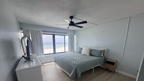 A bedroom with a bed, a desk, a ceiling fan, a window with a view, and a small bedside table. - Breakers C52 - Direct Gulf Front (Orange Beach)