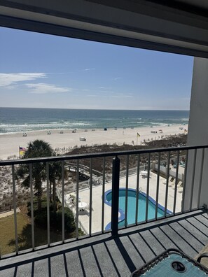 Ein Balkon mit Blick auf einen Strand, ein Schwimmbad und eine Flagge.