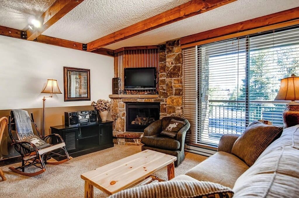 A cozy living room with a stone fireplace, a television, and comfortable seating.