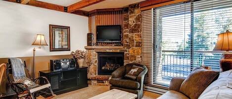 A cozy living room with a stone fireplace, a television, and comfortable seating.