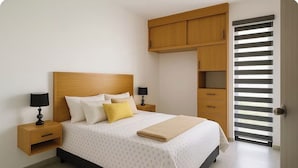 Een slaapkamer met een bed, nachtkastjes, een kledingkast en een schuifdeur.