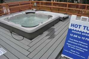 A hot tub on a wooden deck with a sign indicating hot tub hours and noise ordinance enforcement. - Powder Ridge 208  - close to lifts and town! (Breckenridge)