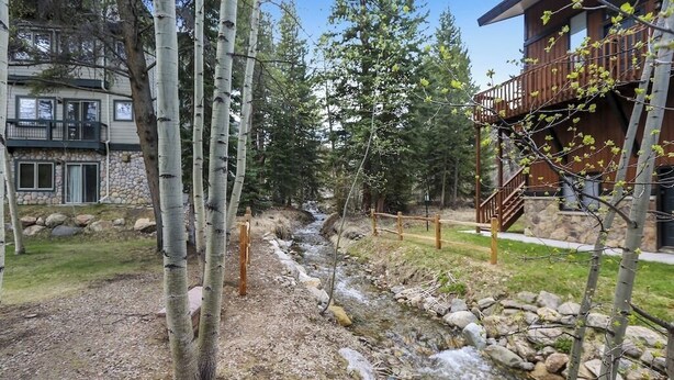 A residential area with a stream, trees, and a wooden deck. - Four O'Clock Lodge Condo- close to lifts and town! (Breckenridge)