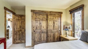 A bedroom with a large bed, wooden wardrobe, and a window with a view. - Four O'Clock Lodge Condo- close to lifts and town! (Breckenridge)