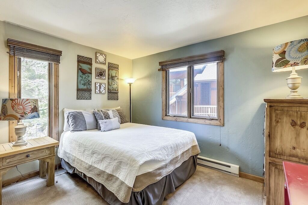 Une chambre à coucher avec un lit, une table de chevet, une lampe et des œuvres d’art murales.