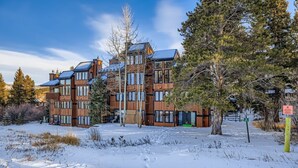 Useita kerroksia sisältävä puinen rakennus, jossa on suuret ikkunat ja lumipeitteinen maisema.