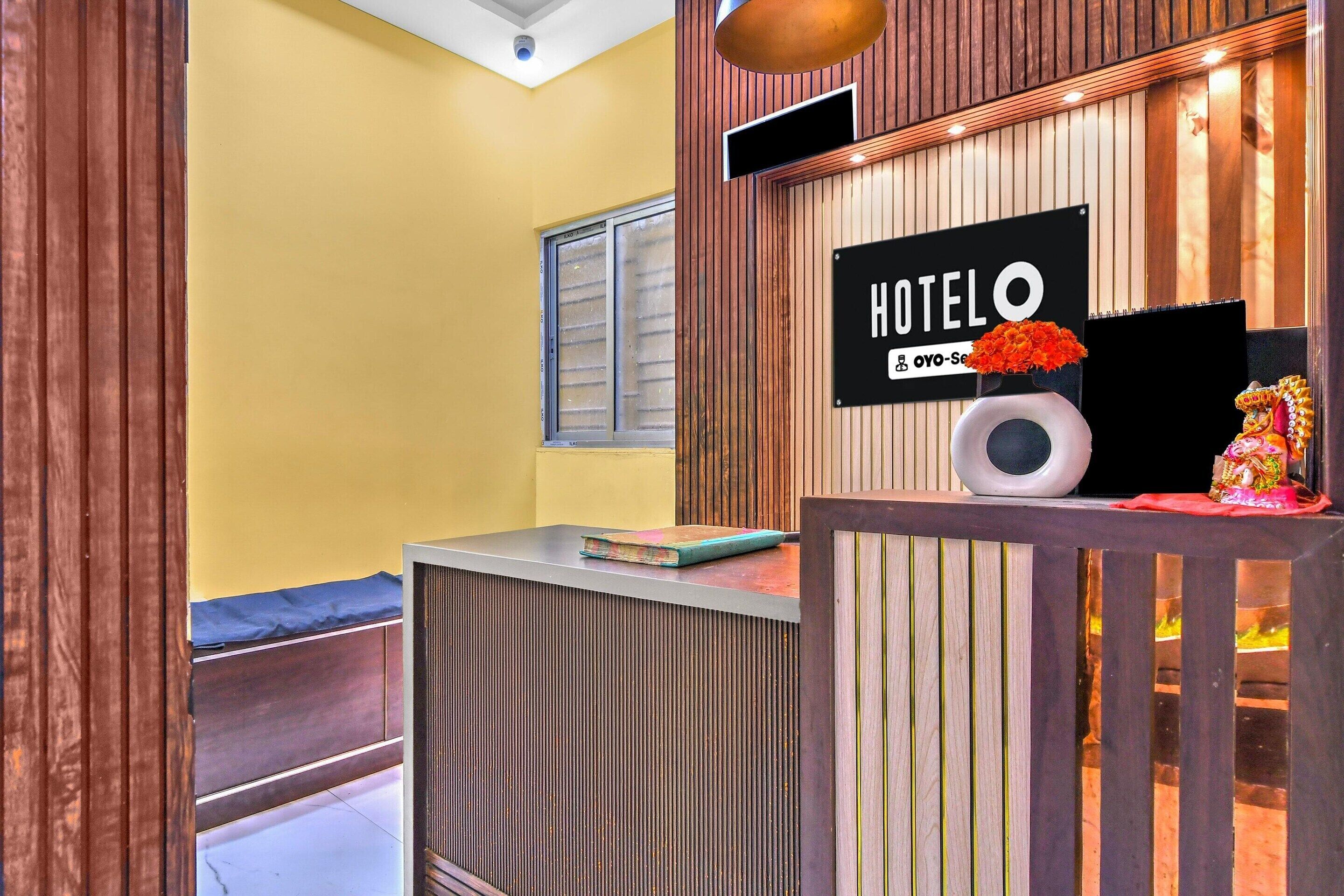 A reception desk with a sign reading 'HOTEL' and a decorative vase with flowers.