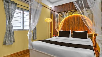 A bedroom with a bed, curtains, a nightstand, and a wall-mounted lamp.