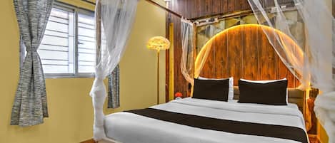 A bedroom with a bed, curtains, a nightstand, and a wall-mounted lamp.