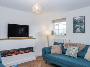 Una sala de estar moderna con un televisor de pantalla plana, chimenea, un sofá color turquesa y un cuadro en la pared.