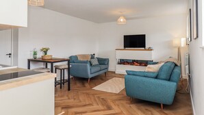 A modern living room with a sofa, a TV mounted on the wall, and a fireplace. - Shamrock (Exeter)