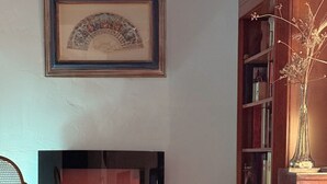 Un salon chaleureux avec une cheminée, une bibliothèque et un plaid à motifs sur un canapé.