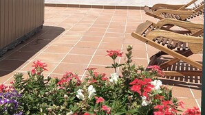 Une terrasse avec un mur blanc, un banc en bois et un jacuzzi.