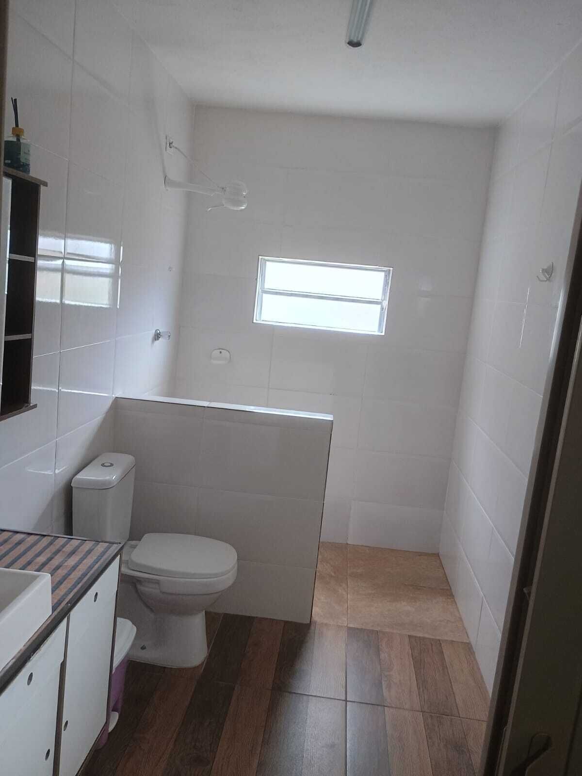 Un baño pequeño y funcional con inodoro, una ventana y paredes de azulejos.