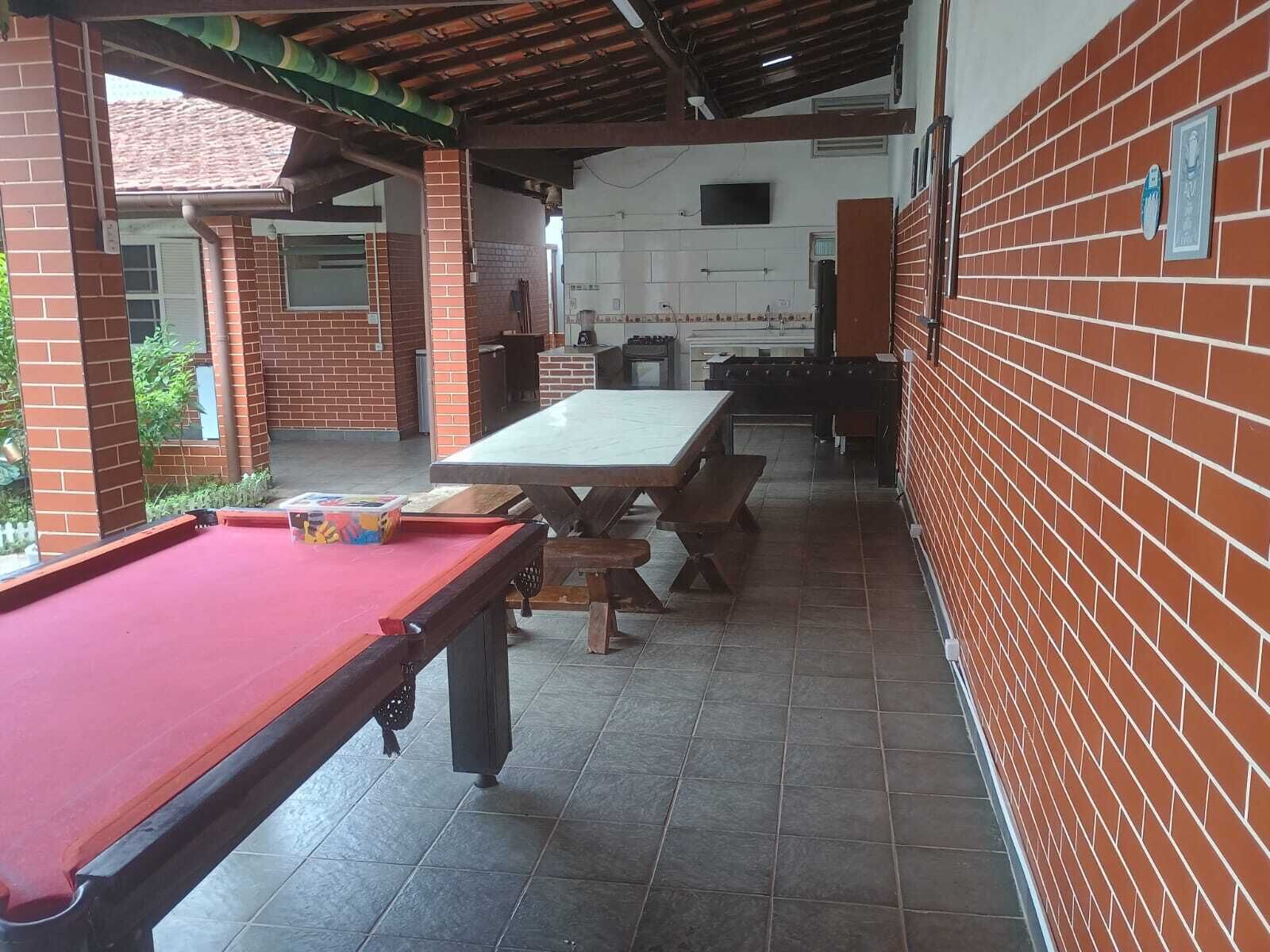 Een biljart, een lange eettafel en een keuken met een bakstenen muur en betegelde vloer.