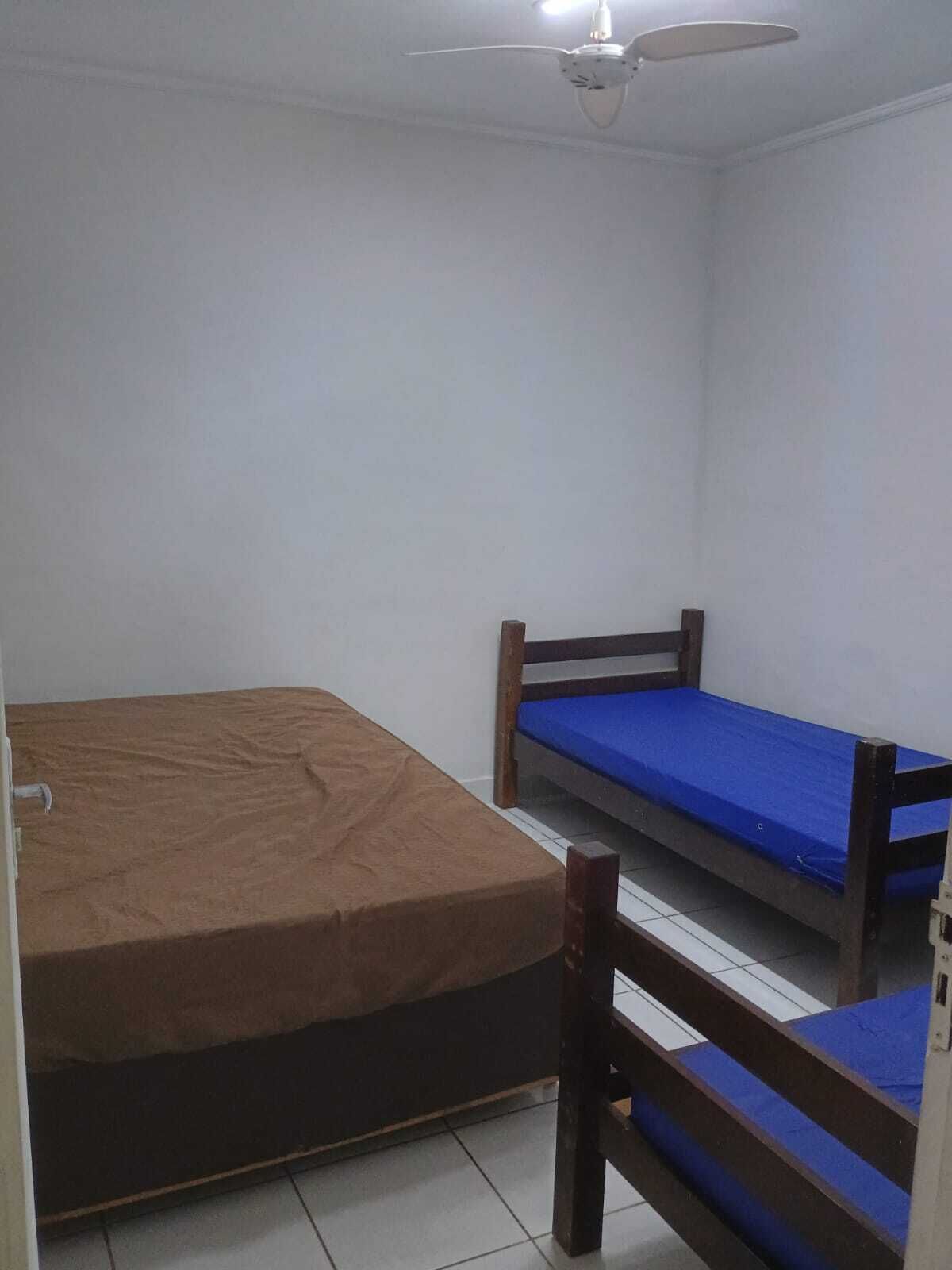 Un dormitorio con dos literas, un ventilador de techo y paredes blancas.