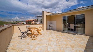 A rooftop patio with a tiled floor, a wooden table and chairs, and a glass door leading to an indoor area. - Apartments in Jd. Centenario in Pocos de Caldas - Clds (Poços de Caldas)