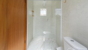 A bathroom with a glass-enclosed shower, a toilet, and a wooden door. - Apartments in Jd. Centenario in Pocos de Caldas - Clds (Poços de Caldas)