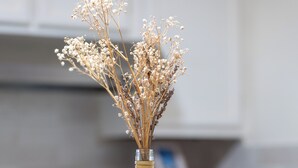 Un vaso di vetro trasparente con fiori secchi su un tavolo di legno in cucina.