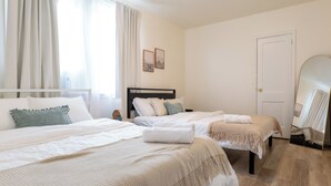 Camera d'albergo con due letti, un grande specchio e una porta.