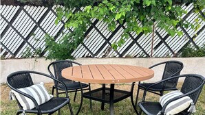 Un tavolo rotondo in legno con quattro sedie nere in vimini, ognuna con cuscini a righe.