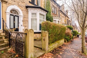 Une rue résidentielle bordée de maisons mitoyennes, avec une entrée sécurisée et un trottoir ombragé par des arbres.