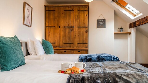 Ein Schlafzimmer mit einem Bett, Kissen, einem Holzschrank, einer kleinen Ablage mit einer Pflanze und einem Schild an der Wand.