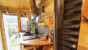 A rustic kitchen with wooden walls, a sink, and a window overlooking a garden. - Old Rosie (Grantham)
