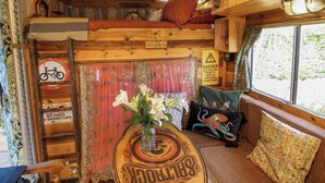 A cozy cabin interior with a bunk bed, a table with a vase of flowers, and a window with a view of trees. - Old Rosie (Grantham)