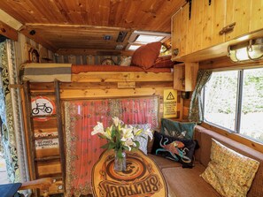 A cozy cabin interior with a bunk bed, a table with a vase of flowers, and a sign warning of ice falling from the ceiling. - Old Rosie (Grantham)