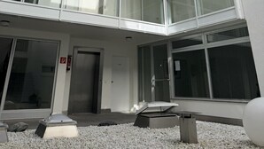 Un edificio de varios pisos con fachada de vidrio, techo plano y una puerta con extintor.