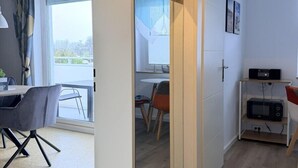 Un apartamento moderno con comedor, cocina equipada con microondas y un ventanal grande.