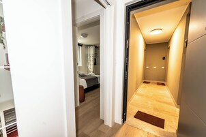 Un corridoio che porta a una camera da letto con un letto, un comodino e una finestra con tende.