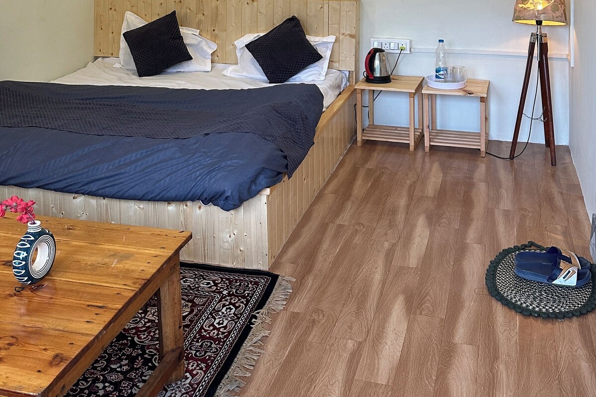 Une chambre d’hôtel avec un lit, une table de chevet, une lampe et un ventilateur de plafond.