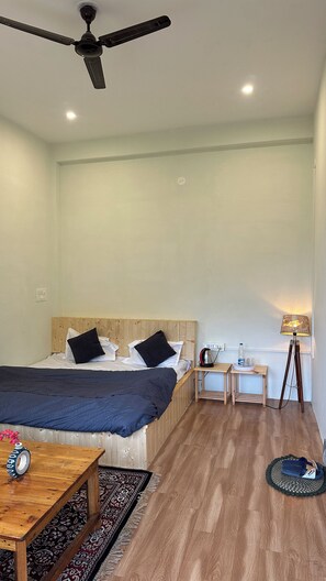Una habitación de hotel con cama, mesita de noche, lámpara y ventilador de techo.