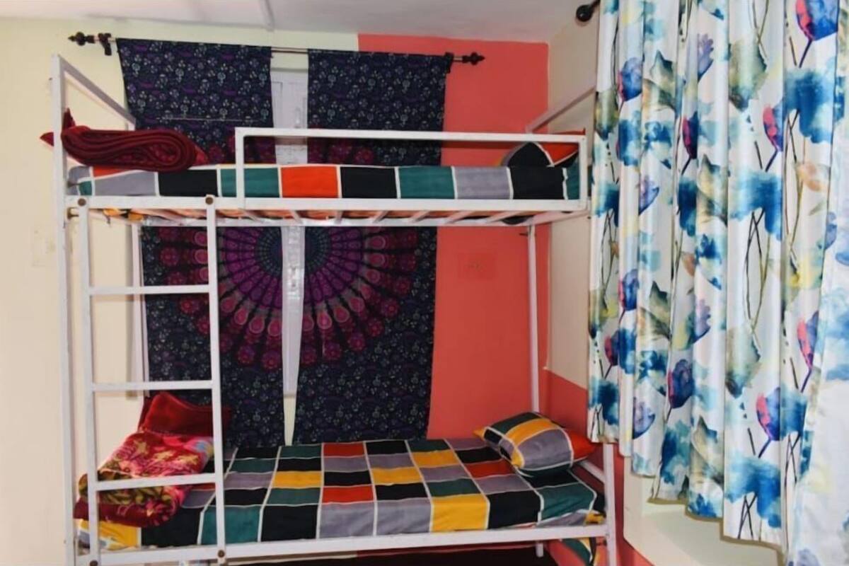 A bunk bed with a checkered bedspread and a colorful tapestry on the wall.