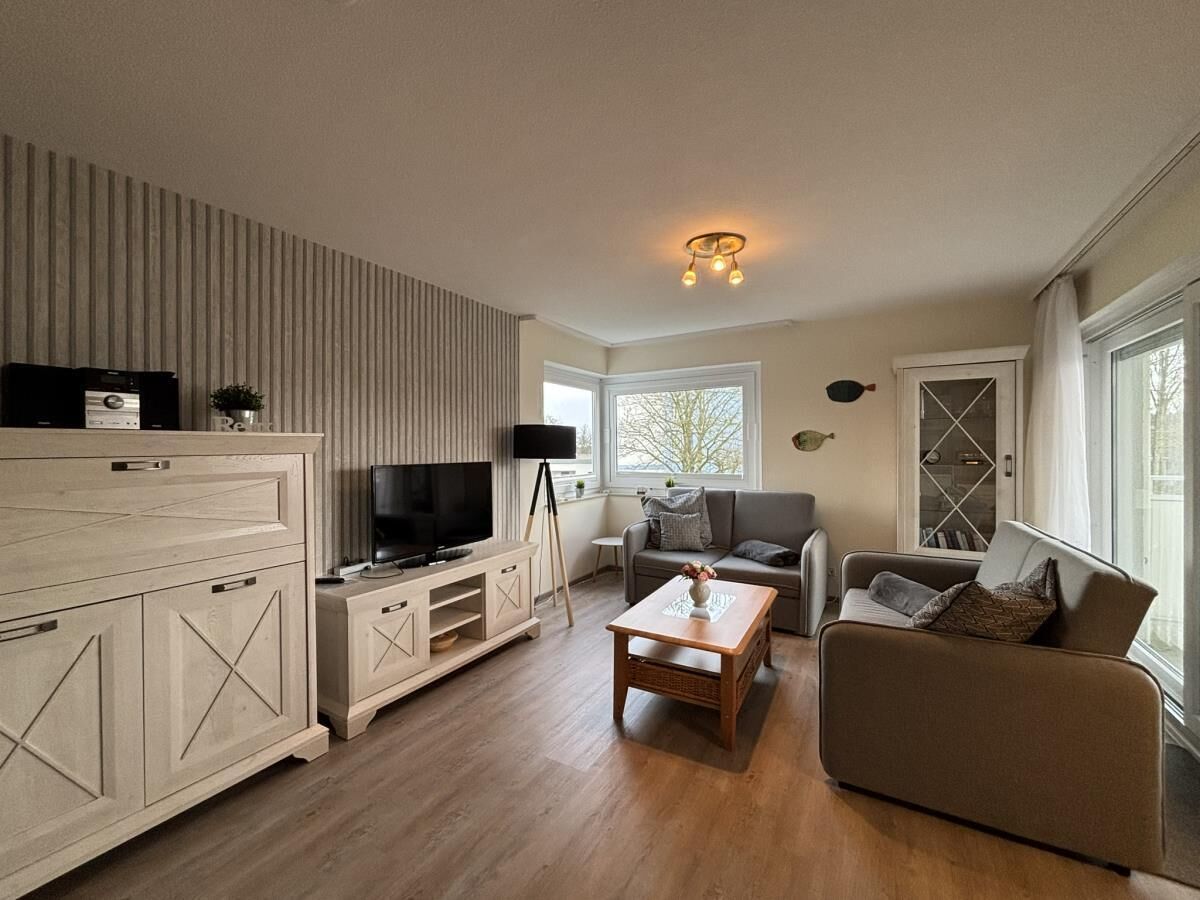 Uma sala de estar moderna com televisão, sofá e mesa de centro.