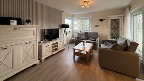 Ett modernt vardagsrum med en TV, en soffa och ett soffbord.