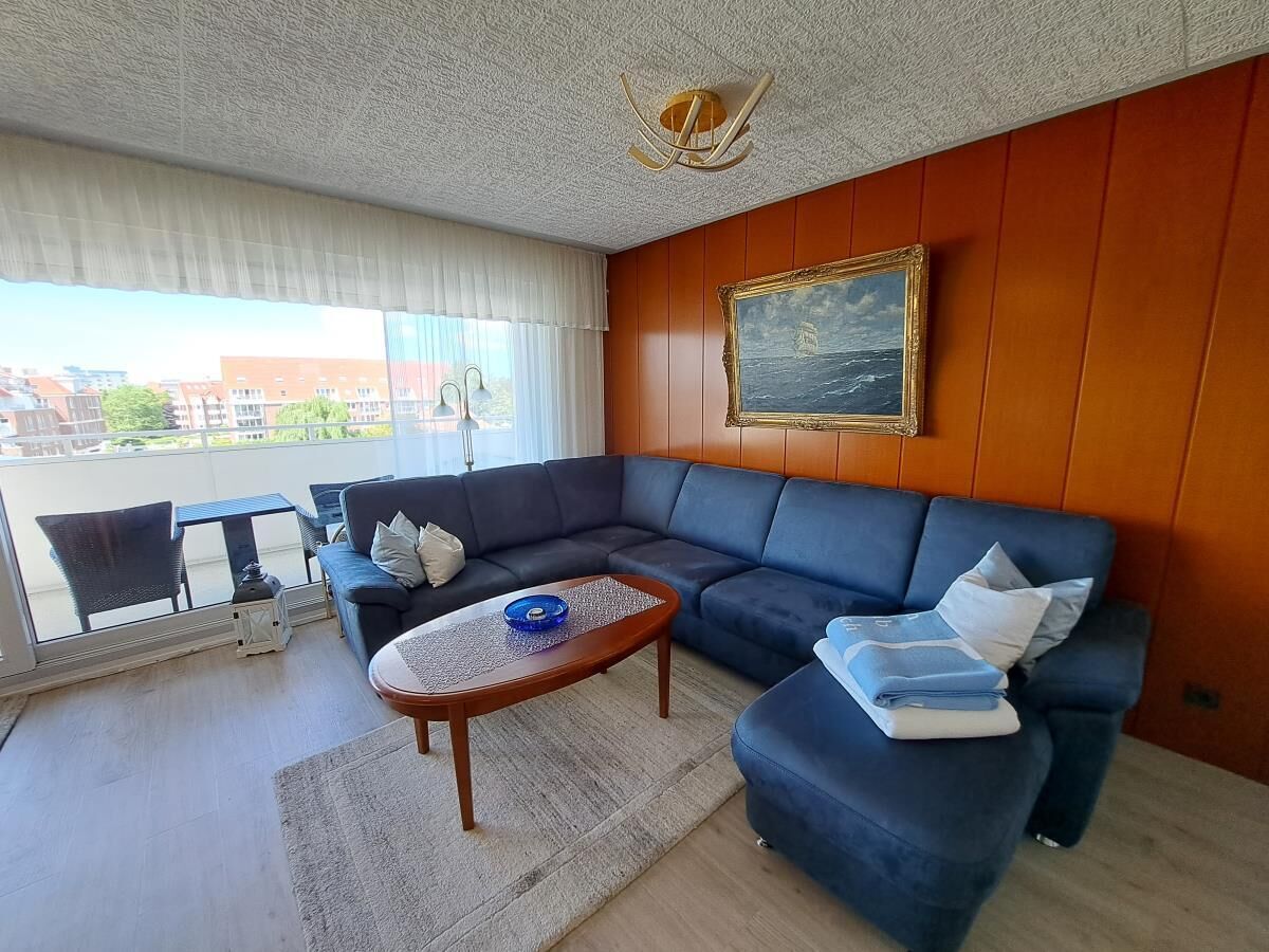 En stue med en mørkeblå sofa, et træbord og et billede på væggen.