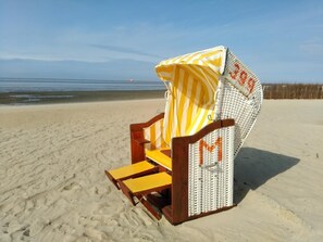 A beach chair with a striped canopy on a sandy beach. - Poseidon House, Apartment POS34 (Cuxhaven)