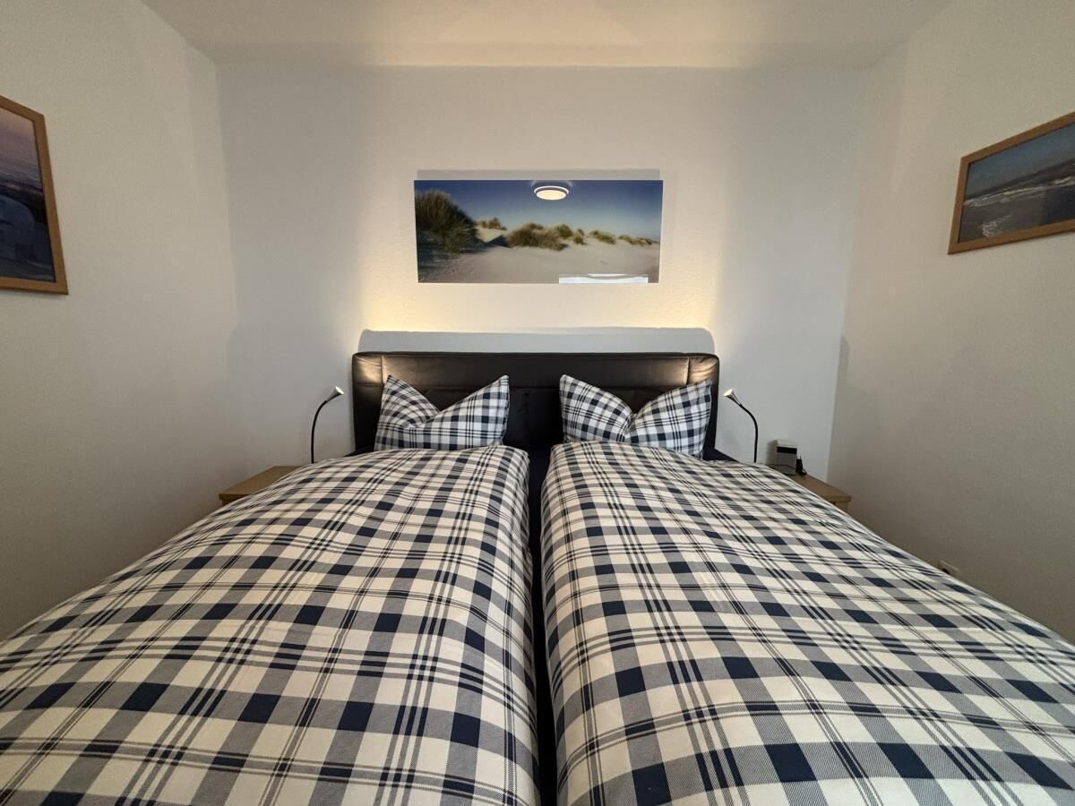 Een slaapkamer met twee bedden, elk met een geruit sprei, hoofdbord en een aan de muur bevestigd schilderij.