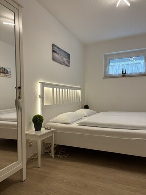 A bedroom with a bed, bedside table, and a window with a view. - Poseidon House, Apartment POS03 (Cuxhaven)