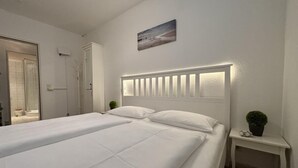 Hotellihuone, jossa on suuri sänky, yöpöytä, jossa on kasvi, ja ikkuna, josta on näkymä.