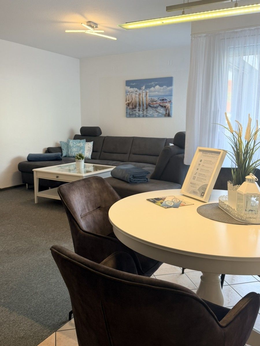 A modern living room with a sofa, a coffee table, and a dining table with chairs.