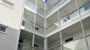Monikerroksinen rakennus, jossa on lasijulkisivu, useita parvekkeita ja pieni suihkulähde sisältävä sisäpiha.